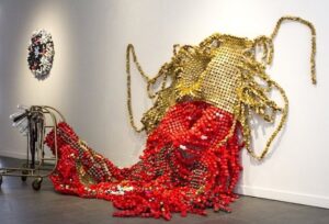 Driedimensionale textielsculptuur met rode en gouden kralen op de vloer