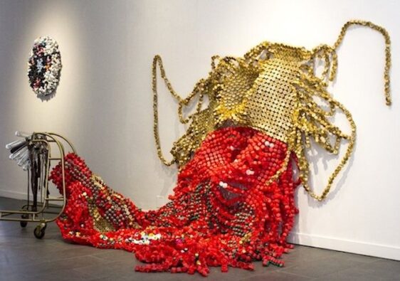 Driedimensionale textielsculptuur met rode en gouden kralen op de vloer