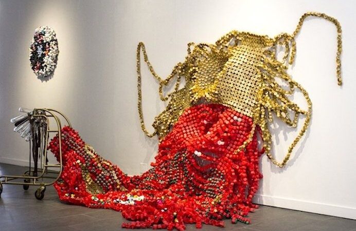 Driedimensionale textielsculptuur met rode en gouden kralen op de vloer