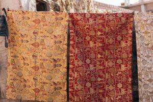 Gedessineerde wandkleden hangen buiten aan haken te luchten