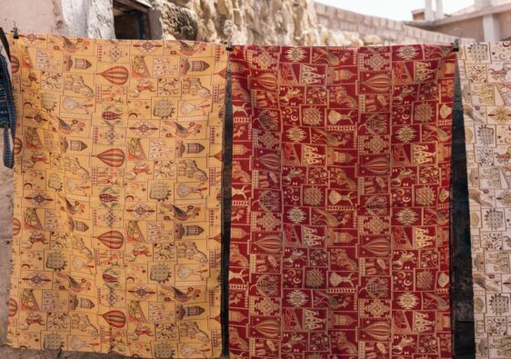 Gedessineerde wandkleden hangen buiten aan haken te luchten