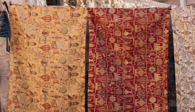 Gedessineerde wandkleden hangen buiten aan haken te luchten